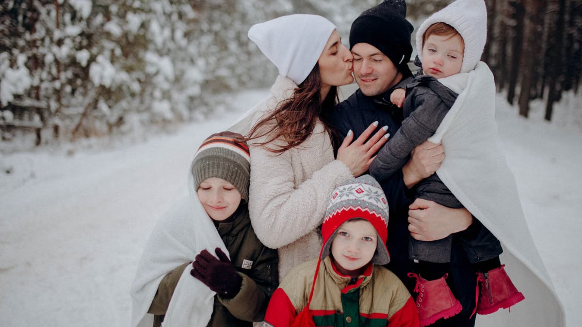A joyful family enjoying a snowy day in a forest, wrapped in warm clothing.